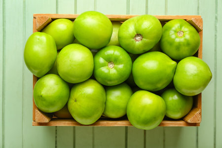 Box with fresh green tomatoes on wooden backgroundの写真素材