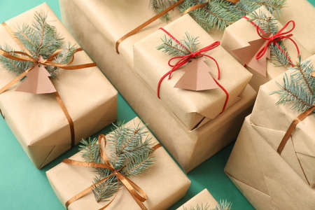Christmas presents with fir branches on color background