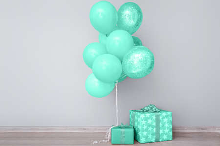Mint balloons and gift boxes near gray wallの写真素材