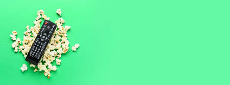 Modern TV remote control with popcorn on green background with space for textの写真素材