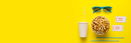 Bucket of tasty popcorn with 3D glasses, cup of cola drink and cinema tickets on yellow background with space for textの写真素材