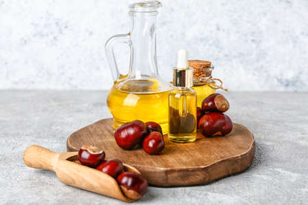 Wooden board with essential oil and fresh chestnuts on tableの写真素材