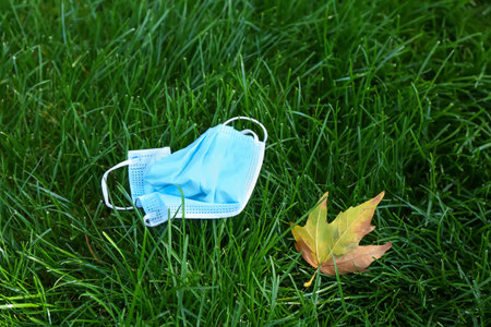 Used medical mask on grass in park