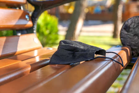 Used medical mask on bench in park