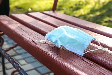 Used medical mask on bench in park