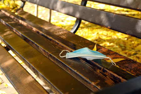 Used medical mask on bench in parkの写真素材