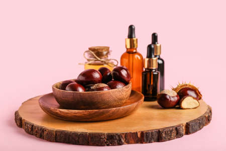 Wooden board with fresh chestnuts and cosmetics on color backgroundの写真素材