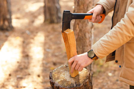 Male tourist chopping wood in forest, closeup