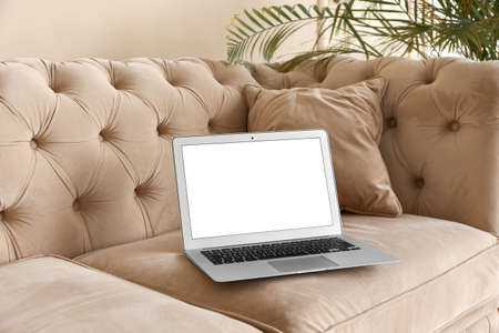 Laptop with blank screen on sofa near beige wallの写真素材