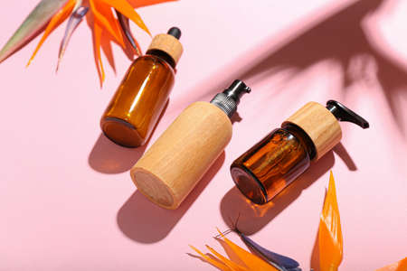 Bottles of cosmetic products and strelitzia flowers on pink backgroundの写真素材