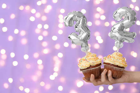 Woman holding Birthday cupcakes against blurred backgroundの写真素材