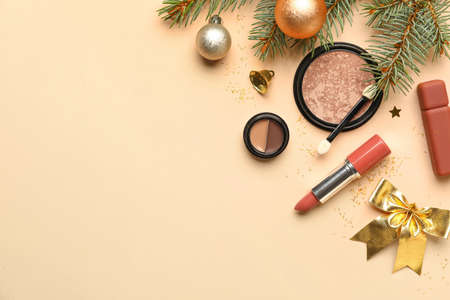 Decorative cosmetics, fir tree branch and Christmas decor on color backgroundの写真素材