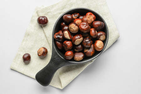 Frying pan with chestnuts on white background