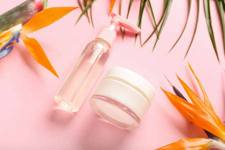 Cosmetic products and strelitzia flowers on pink background