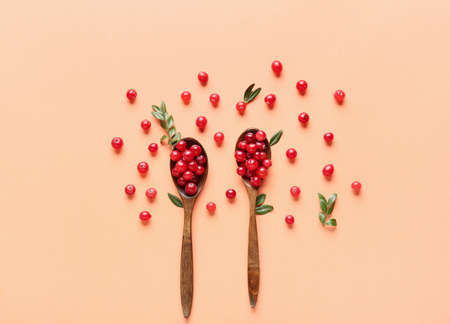 Wooden spoons with lingonberries and leaves on beige backgroundの写真素材