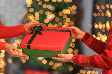 Women with Christmas present at home in the evening, closeup