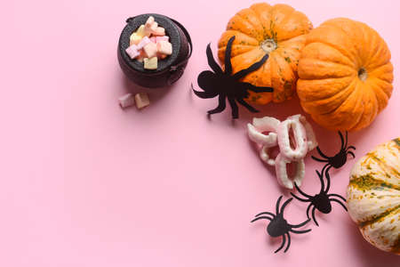 Halloween pumpkins with decor and candies on pink backgroundの写真素材