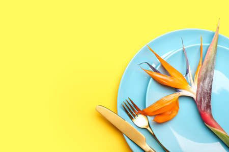 Simple table setting with bird of paradise flower on yellow backgroundの写真素材