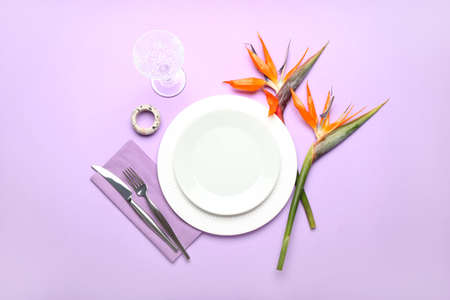 Simple table setting with bird of paradise flowers on purple background