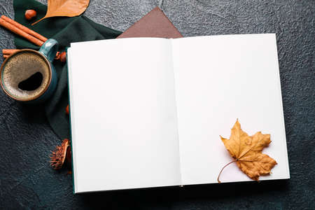 Opened book with blank pages, cup of coffee and autumn decor on dark backgroundの写真素材