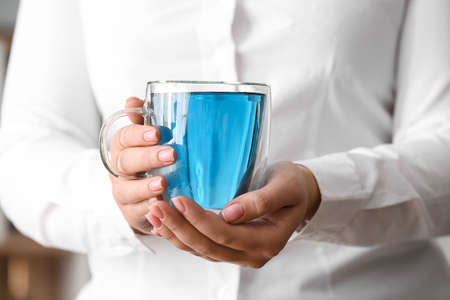 Woman with cup of butterfly pea flower tea, closeup