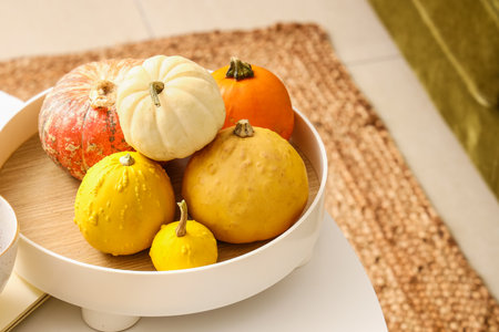 Tray with fresh pumpkins on table in room