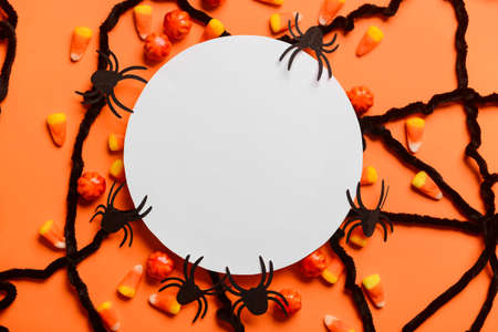 Blank paper sheet with candies and Halloween decor on red backgroundの写真素材