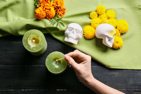 Woman lighting candle on dark wooden background. Mexico's Day of the Dead (El Dia de Muertos)