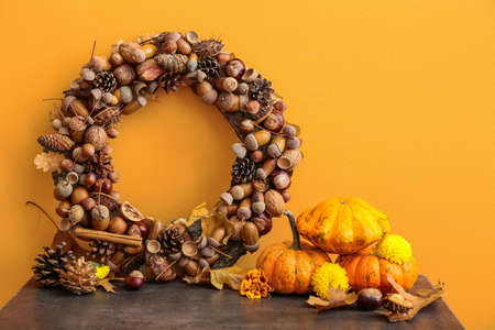 Beautiful acorn wreath and pumpkins near orange wallの写真素材