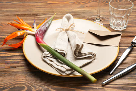 Table setting with beautiful bird of paradise flower on dark wooden background