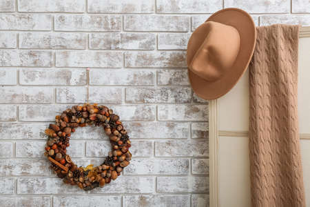 Beautiful acorn wreath on light brick wall and clothes in roomの写真素材