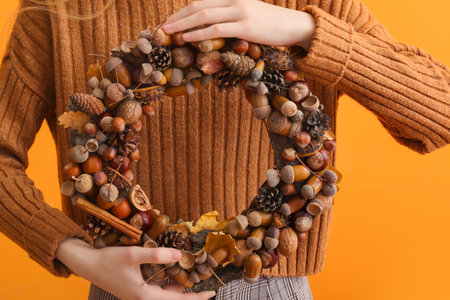 Woman with beautiful acorn wreath on orange background, closeupの写真素材