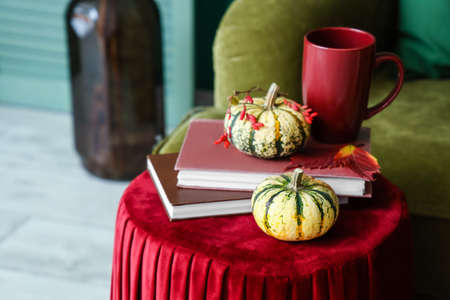 Books, pumpkins and cup of tea on table in roomの写真素材