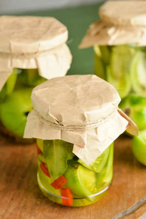 Jars with canned green tomatoes on tableの写真素材