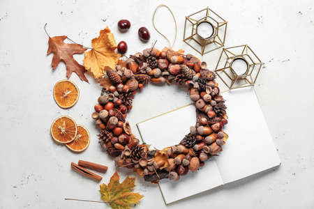 Beautiful wreath made of pine cones and acorns with candlesticks on light backgroundの写真素材