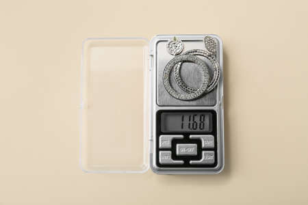 Jewelry scales with earrings on beige background
