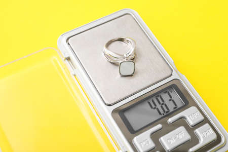 Jewelry scales with ring on yellow background