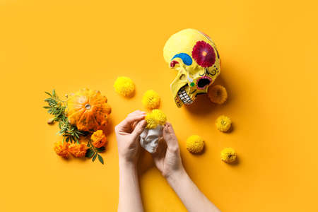 Woman with human skull and flowers on yellow background. Mexico's Day of the Dead (El Dia de Muertos)の写真素材