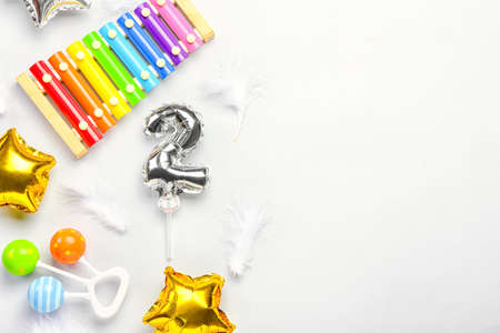 Silver balloon in shape of figure 2, toys and feathers on light backgroundの写真素材