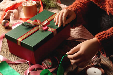 Woman decorating Christmas gift box at tableの写真素材