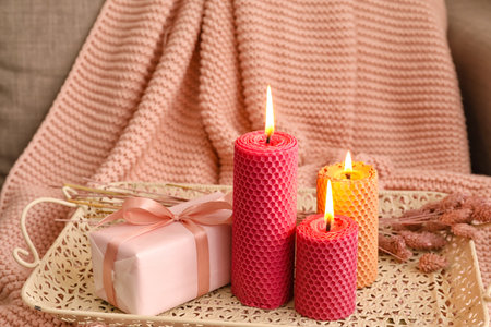 Tray with burning candles and gift box on sofaの写真素材