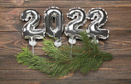 Figure 2022 made of silver balloons and fir tree branches on wooden backgroundの写真素材