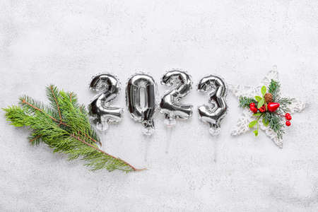 Figure 2023 made of silver balloons and Christmas decor on light background