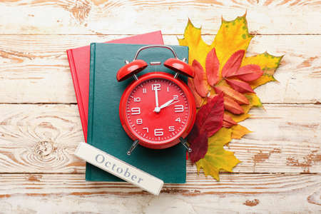 Alarm clock, notebooks and autumn leaves on wooden backgroundの写真素材