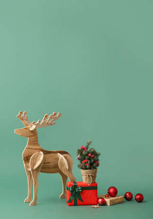 Wooden reindeer with small Christmas tree and gifts on green backgroundの写真素材