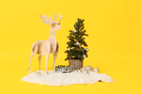 Wooden reindeer with Christmas tree on yellow backgroundの写真素材
