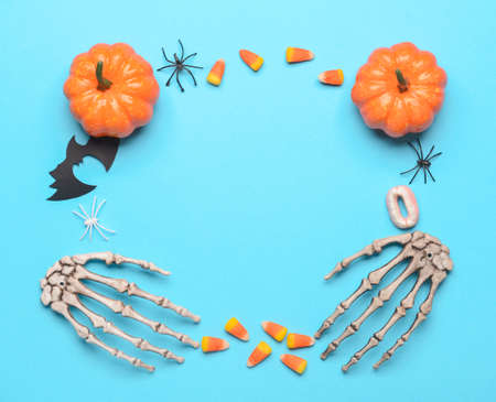Frame made of pumpkins, candies and Halloween decor on blue background