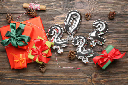Balloons in shape of figure 2022 and Christmas presents on wooden backgroundの写真素材