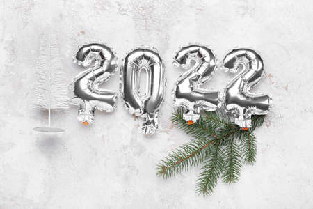 Silver balloons in shape of figure 2022 and Christmas decor on light backgroundの写真素材