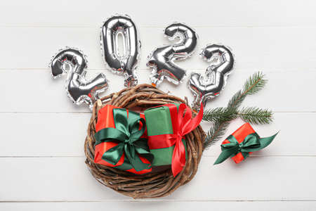 Silver balloons in shape of figure 2023 and Christmas presents on white wooden backgroundの写真素材